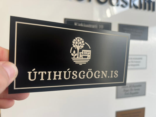 Svart álskilti með merki Útihúsgögn.is og hvítum ramma
