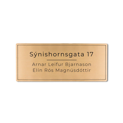 Gyllt skilti á póstkassa með heimilisfangi.