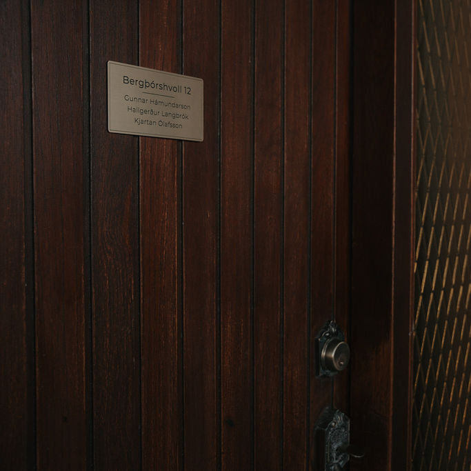 Gyllt nafnaskilti með heimilisfangi og nöfnum.