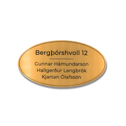 Gyllt sporöskjulaga nafnaskilti með heimilisfangi.