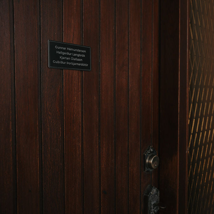 Svart nafnaskilti á hurð í miðstærð. Vinsælasta stærðin fyrir fjölskyldur.